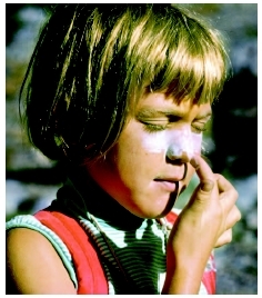 Young girl applies sunscreen to her face to protect herself from sun damage. ( Lowell Georgia/Corbis.)